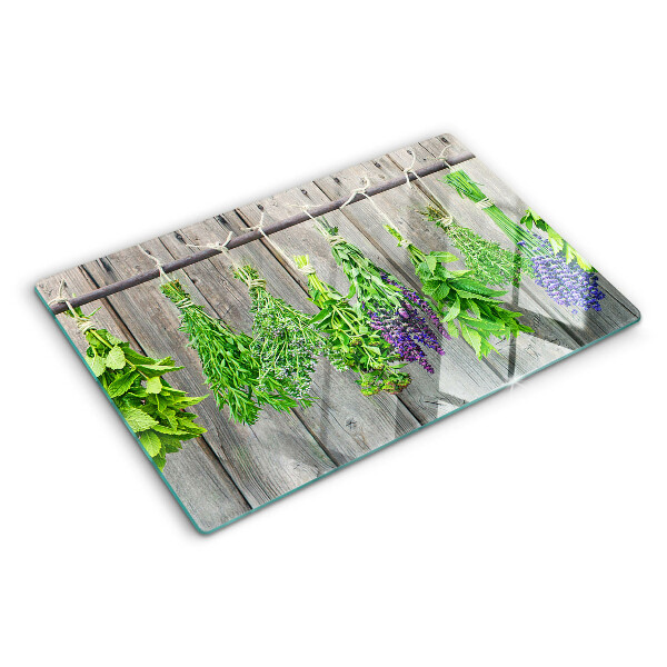 Szklana deska kuchenna z motywem suszonych ziół na tle drewna