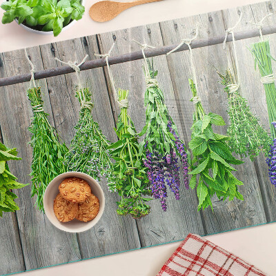 Szklana deska kuchenna z motywem suszonych ziół na tle drewna