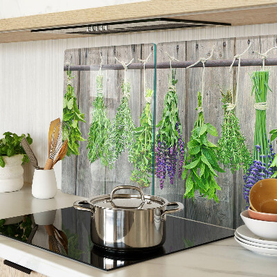 Szklana deska kuchenna z motywem suszonych ziół na tle drewna