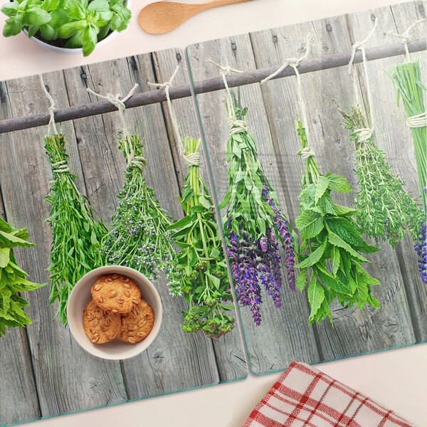 Szklana deska kuchenna z motywem suszonych ziół na tle drewna