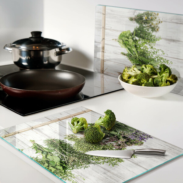 Szklana deska do krojenia z motywem ziół na tle drewnianym
