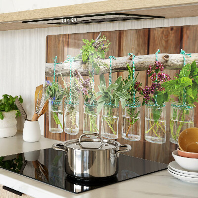 Szklana deska kuchenna z motywem ziół w słoikach na tle drewna