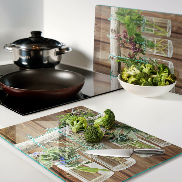 Szklana deska kuchenna z motywem ziół w słoikach na tle drewna