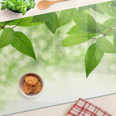 Szklana deska kuchenna z motywem liści na tle rozmytej zieleni