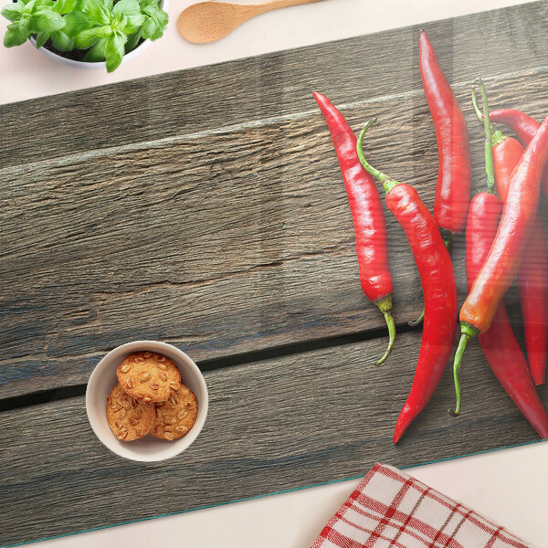 Szklana deska kuchenna z motywem papryczek chili na tle drewna