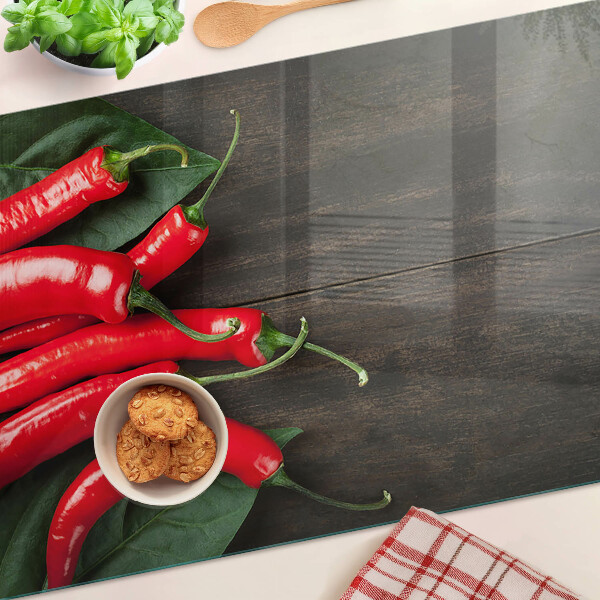 Szklana deska do krojenia z nadrukiem papryczek chili na tle drewnianego blatu