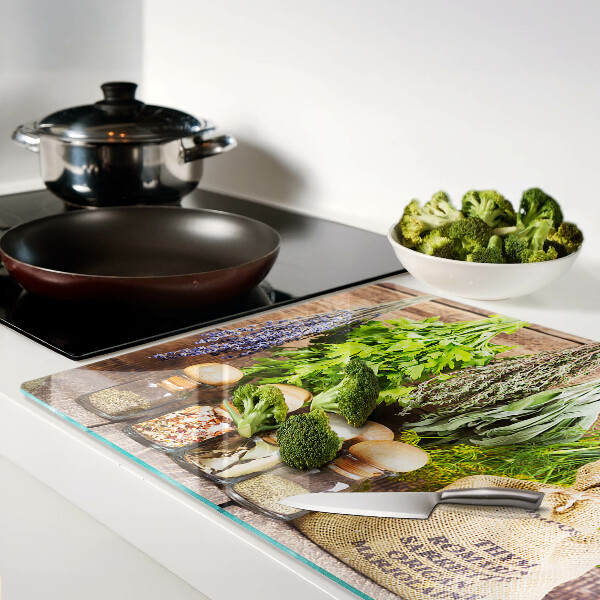 Szklana deska do krojenia z motywem ziół i przypraw na tle drewna