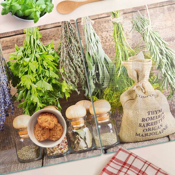 Szklana deska do krojenia z motywem ziół i przypraw na tle drewna