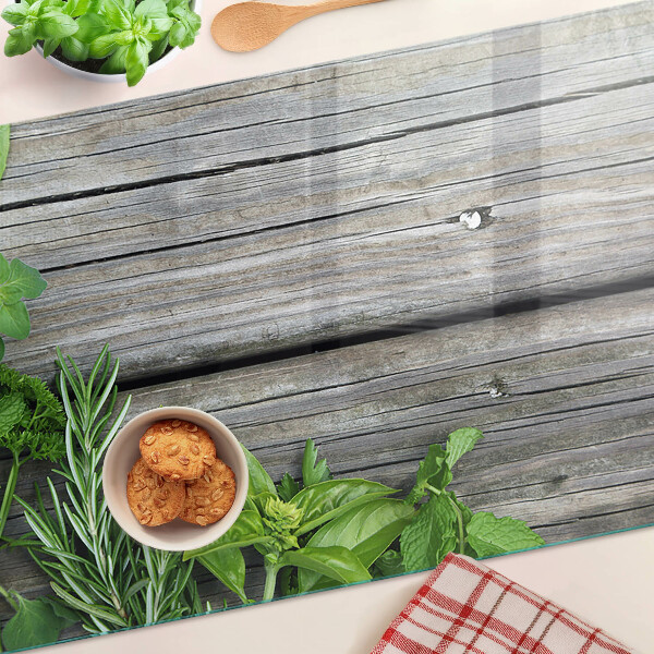 Szklana deska kuchenna z motywem zielonych ziół na drewnianym tle