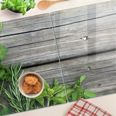 Szklana deska kuchenna z motywem zielonych ziół na drewnianym tle