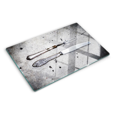 Szklana deska kuchenna ze wzorem sztućców na tle betonu